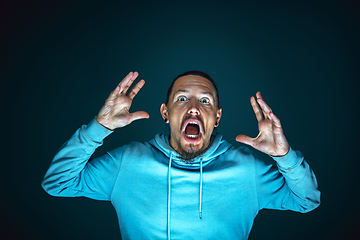 Image showing Close up portrait of young crazy scared and shocked man isolated on dark background