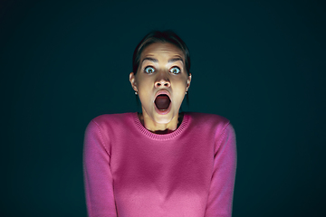 Image showing Close up portrait of young crazy scared and shocked woman isolated on dark background