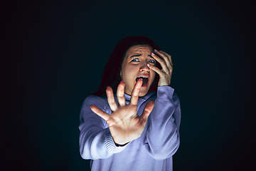 Image showing Close up portrait of young crazy scared and shocked woman isolated on dark background