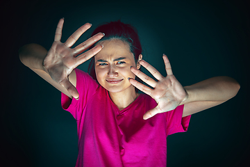 Image showing Close up portrait of young crazy scared and shocked woman isolated on dark background