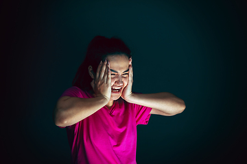 Image showing Close up portrait of young crazy scared and shocked woman isolated on dark background