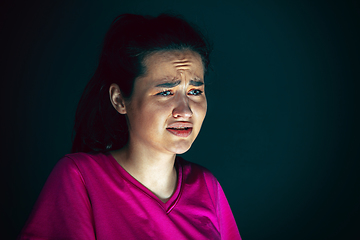 Image showing Close up portrait of young crazy scared and shocked woman isolated on dark background