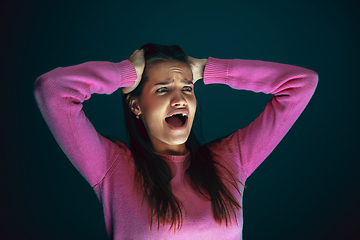 Image showing Close up portrait of young crazy scared and shocked woman isolated on dark background