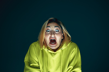 Image showing Close up portrait of young crazy scared and shocked woman isolated on dark background