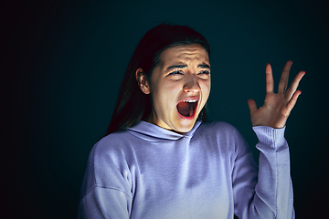 Image showing Close up portrait of young crazy scared and shocked woman isolated on dark background