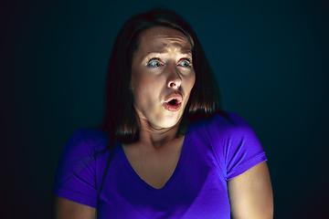 Image showing Close up portrait of young crazy scared and shocked woman isolated on dark background