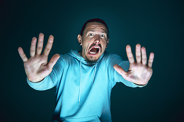 Image showing Close up portrait of young crazy scared and shocked man isolated on dark background
