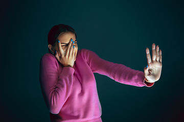 Image showing Close up portrait of young crazy scared and shocked woman isolated on dark background