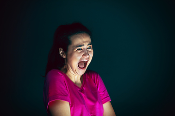 Image showing Close up portrait of young crazy scared and shocked woman isolated on dark background