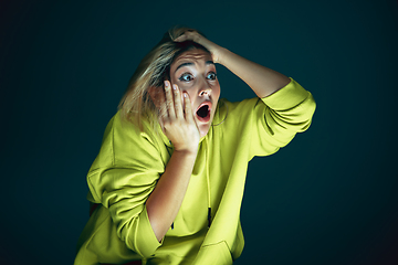 Image showing Close up portrait of young crazy scared and shocked woman isolated on dark background