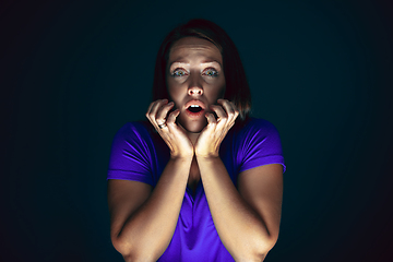 Image showing Close up portrait of young crazy scared and shocked woman isolated on dark background