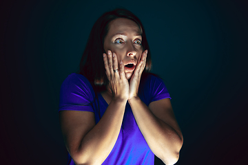 Image showing Close up portrait of young crazy scared and shocked woman isolated on dark background