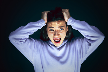Image showing Close up portrait of young crazy scared and shocked woman isolated on dark background