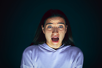 Image showing Close up portrait of young crazy scared and shocked woman isolated on dark background