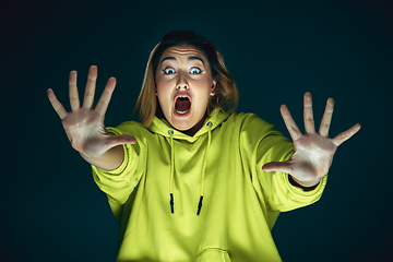 Image showing Close up portrait of young crazy scared and shocked woman isolated on dark background