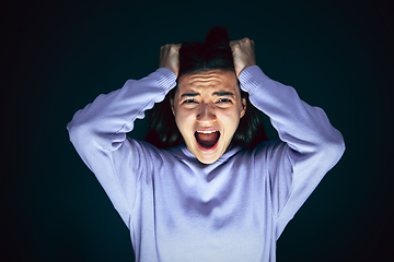 Image showing Close up portrait of young crazy scared and shocked woman isolated on dark background