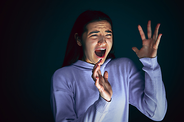 Image showing Close up portrait of young crazy scared and shocked woman isolated on dark background