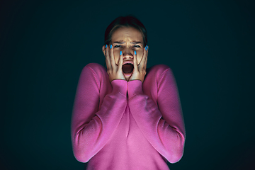 Image showing Close up portrait of young crazy scared and shocked woman isolated on dark background