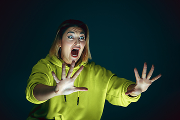 Image showing Close up portrait of young crazy scared and shocked woman isolated on dark background