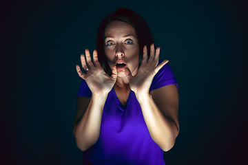 Image showing Close up portrait of young crazy scared and shocked woman isolated on dark background