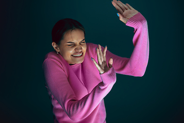 Image showing Close up portrait of young crazy scared and shocked woman isolated on dark background