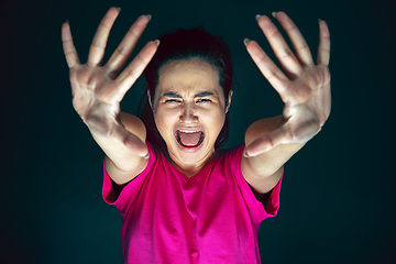 Image showing Close up portrait of young crazy scared and shocked woman isolated on dark background