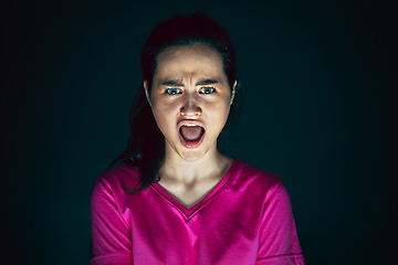 Image showing Close up portrait of young crazy scared and shocked woman isolated on dark background