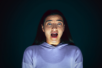 Image showing Close up portrait of young crazy scared and shocked woman isolated on dark background