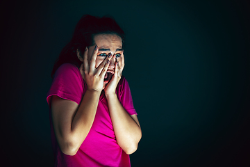 Image showing Close up portrait of young crazy scared and shocked woman isolated on dark background