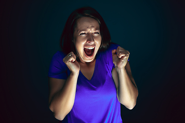 Image showing Close up portrait of young crazy scared and shocked woman isolated on dark background