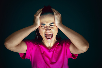 Image showing Close up portrait of young crazy scared and shocked woman isolated on dark background