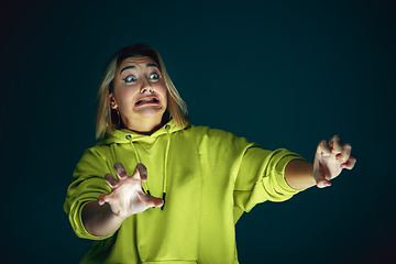 Image showing Close up portrait of young crazy scared and shocked woman isolated on dark background