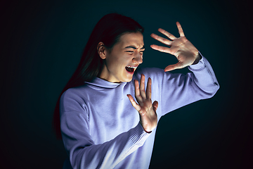 Image showing Close up portrait of young crazy scared and shocked woman isolated on dark background