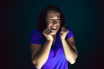 Image showing Close up portrait of young crazy scared and shocked woman isolated on dark background