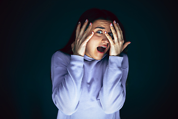 Image showing Close up portrait of young crazy scared and shocked woman isolated on dark background