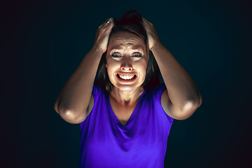 Image showing Close up portrait of young crazy scared and shocked woman isolated on dark background