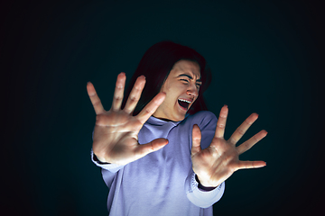 Image showing Close up portrait of young crazy scared and shocked woman isolated on dark background