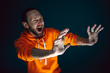 Image showing Close up portrait of crazy scared and shocked man isolated on dark background