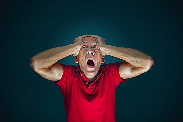 Image showing Close up portrait of crazy scared and shocked man isolated on dark background