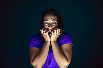 Image showing Close up portrait of young crazy scared and shocked woman isolated on dark background