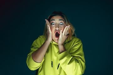 Image showing Close up portrait of young crazy scared and shocked woman isolated on dark background