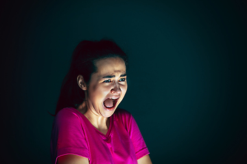 Image showing Close up portrait of young crazy scared and shocked woman isolated on dark background