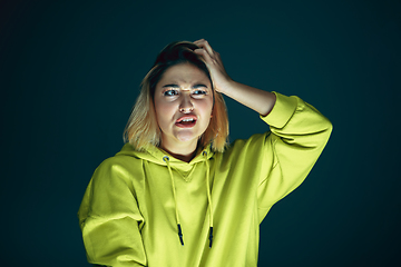 Image showing Close up portrait of young crazy scared and shocked woman isolated on dark background