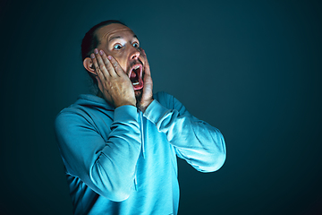 Image showing Close up portrait of young crazy scared and shocked man isolated on dark background