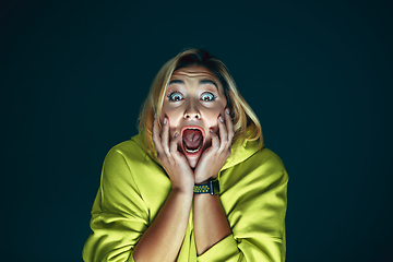 Image showing Close up portrait of young crazy scared and shocked woman isolated on dark background