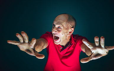 Image showing Close up portrait of crazy scared and shocked man isolated on dark background