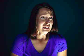 Image showing Close up portrait of young crazy scared and shocked woman isolated on dark background