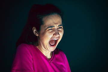 Image showing Close up portrait of young crazy scared and shocked woman isolated on dark background