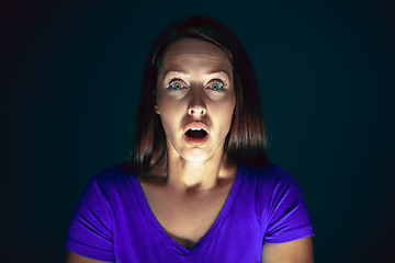 Image showing Close up portrait of young crazy scared and shocked woman isolated on dark background