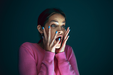 Image showing Close up portrait of young crazy scared and shocked woman isolated on dark background